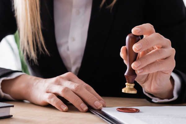 Woman in a suit using a wax seal stamp on legal documents, symbolizing the process of sealing or expunging family violence charges in Texas.