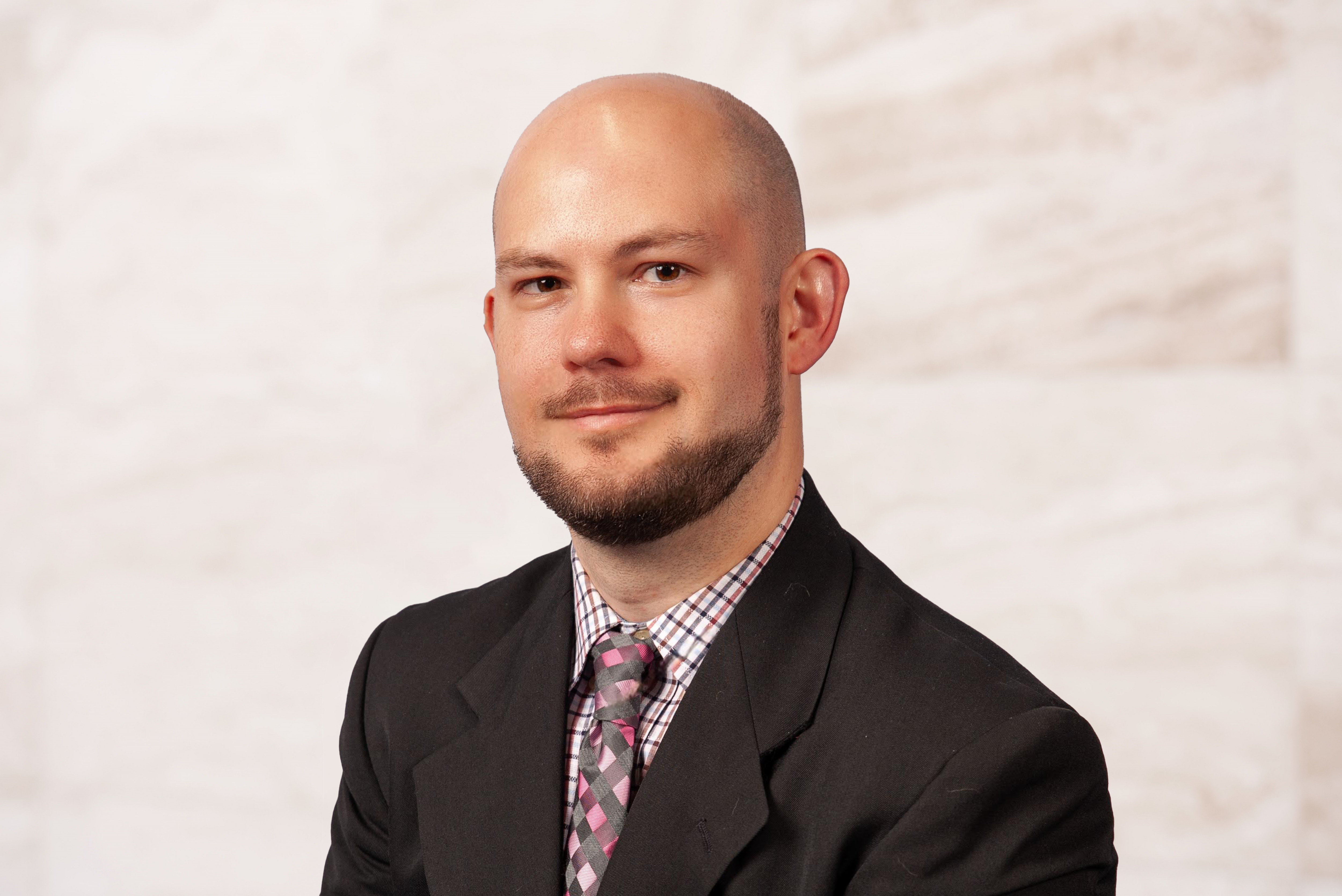 Ricky Whitehead, Associate Attorney at the Law Office of Bryan Fagan, in professional attire with a plaid shirt and patterned tie, against a neutral background, representing legal expertise and community advocacy in Texas.