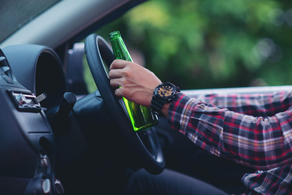 the ultimate resource for dwi cases, asian man holds beer bottle while is driving car