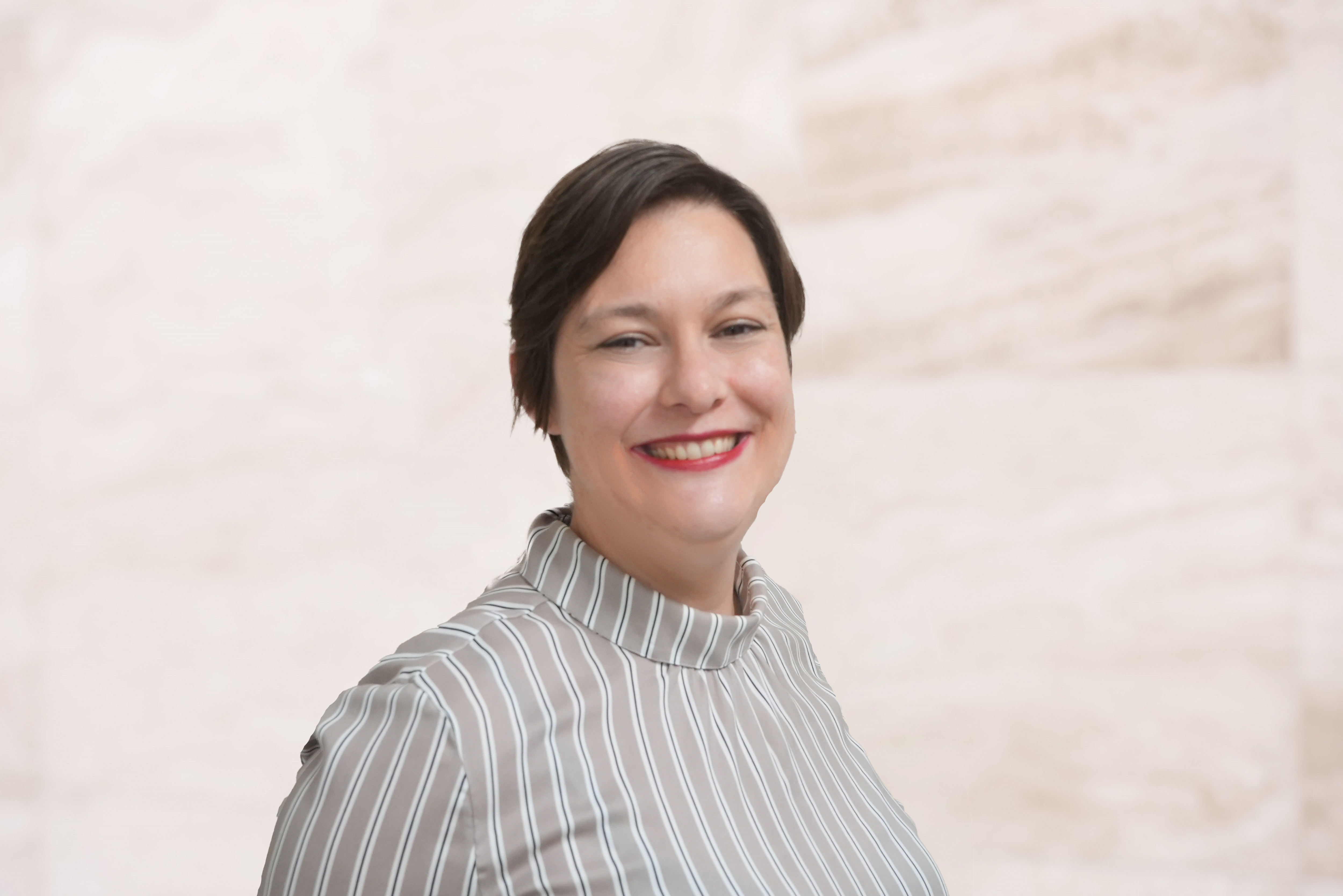 Mary Scherzer, associate attorney at the Law Office of Bryan Fagan, smiling in a professional setting, wearing a striped blouse, advocating for family law and community support.