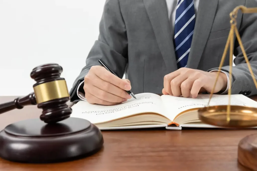 Lawyer in a suit writing notes in a legal book, with a gavel and scales of justice on the desk, symbolizing criminal defense advocacy in Arlington, Texas.