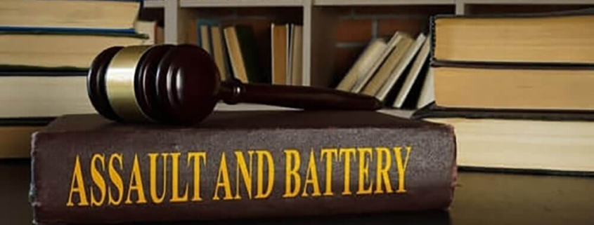 Gavel resting on a book titled "Assault and Battery," surrounded by law books, emphasizing legal themes related to criminal law in Texas.
