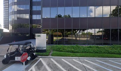 Modern office building exterior with reflective glass windows, featuring a stop sign and a golf cart parked near the entrance, relevant to Bryan Fagan Law Office's Houston location.