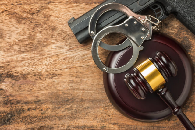 Handcuffs and gavel on wooden surface with a handgun, symbolizing criminal defense and Texas robbery cases.